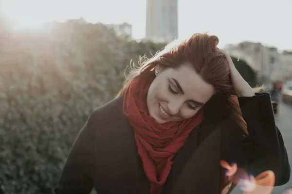 Woman looking down, toucing her hair and smiling