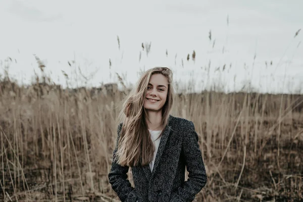 Mode vrouw met lang blond haar gekleed in vacht kijken camera en glimlachen — Stockfoto