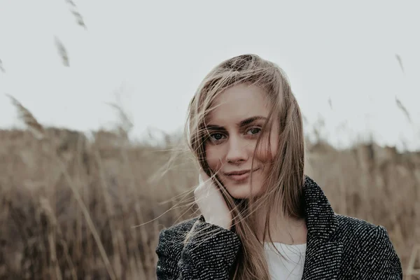 Close-up portret van de vrouw in de camera kijken op lisdodde achtergrond winterjas — Stockfoto
