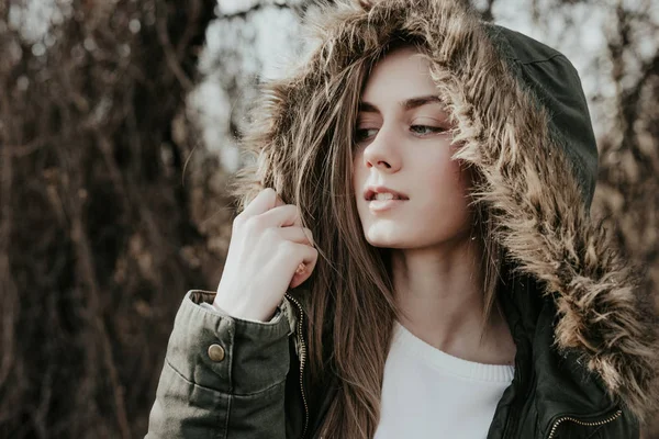 Güzel kadın sıcak yeşil ceket kürk başlık ile kamera poz