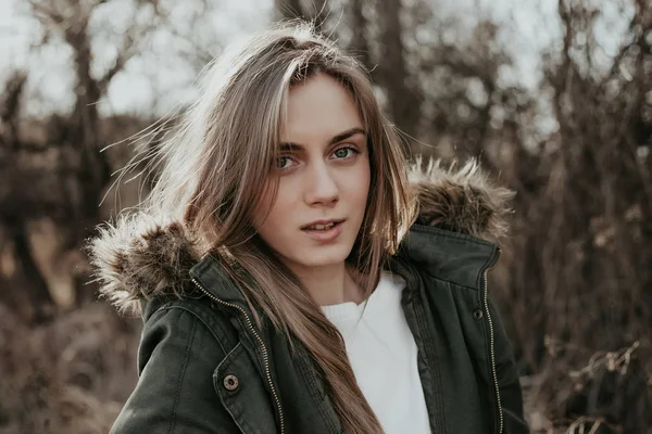 Pretty young european woman with blonde hair and in warm jacket looking at camera outdoor