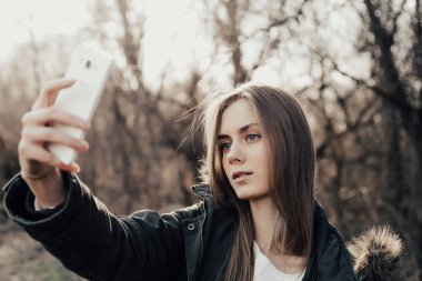 Kadın akıllı telefondan selfie çekiyor.