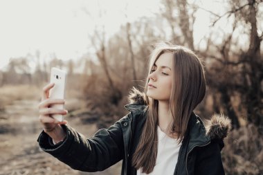 Kadın akıllı telefondan selfie çekiyor.