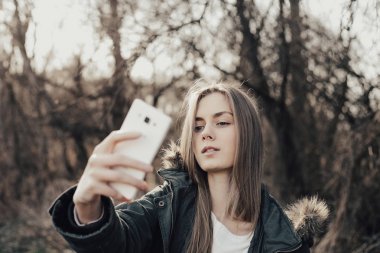 Kadın akıllı telefondan selfie çekiyor.