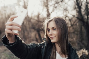 Kadın akıllı telefondan selfie çekiyor.