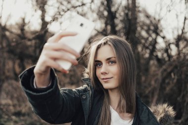 Kadın akıllı telefondan selfie çekiyor.