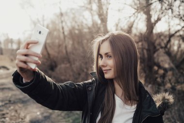 Kadın akıllı telefondan selfie çekiyor.
