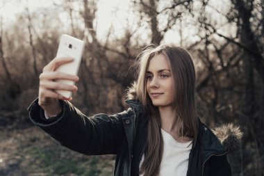 Kadın akıllı telefondan selfie çekiyor.
