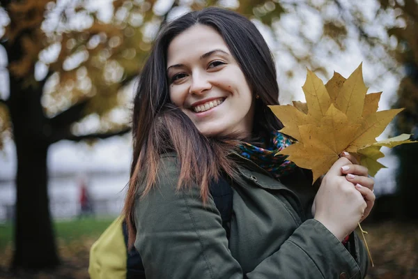 Kameraya bakarak neşeli ve mutlu kadın Park ile sonbahar yaprakları