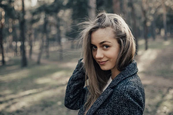 Kameraya bakarak ve gülümseyen montlu sarışın kadın. Oldukça sıcak ceket giymiş uzun sarı saçlı model straighted o saçları bakarak fotoğraf makinesi ve geniş gülümsüyor