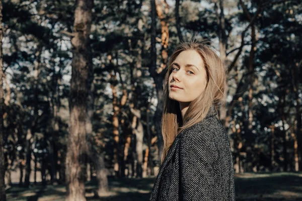 Sarışın kadın kameraya poz arka plan açık ağaç 