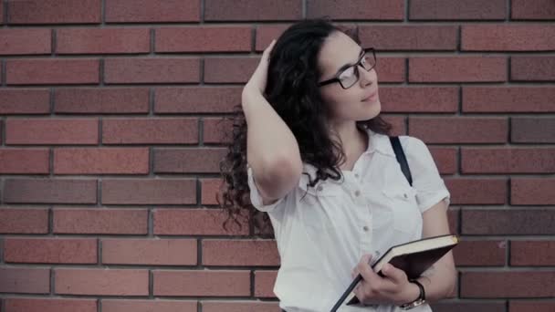Mladá Žena Kudrnatými Vlasy Brýlích Cihlovou Zeď Pozadí Model Vypadá — Stock video