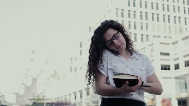 成功した女性は 急いで彼女のノートでノートをとる 白シャツ 黒のスカート メガネに身を包んだ長い巻き毛髪の少女 — ストック動画