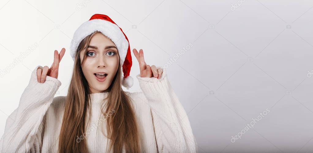 Thw girl in Santa Claus Hat crossed her fingers on hands