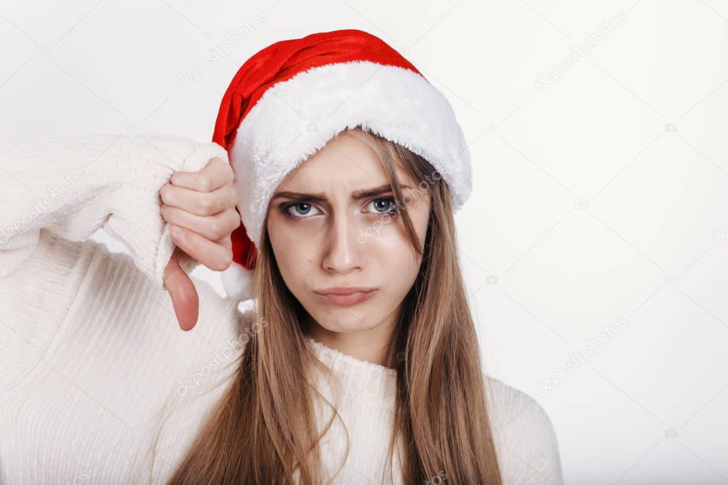 The young woman in santa hat showing thumbs down and make capricious face