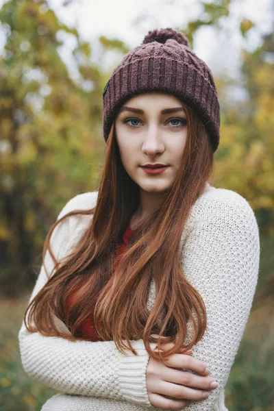얼굴을 카메라 보고에 그녀의 따뜻한 스카프 모자와 스웨터를 그녀는을 배경에서 — 스톡 사진