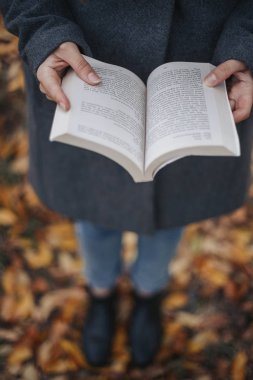 Onu elinde tutan kız kitap açın. Gözleri atış kuşlar. Yüksek açı vurdu. Sonbahar. Açık