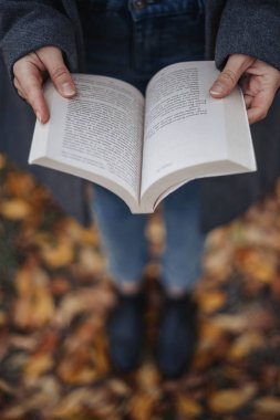 El kitabında tutan kadın. Erkek holding açık kitap eller. Gözleri atış kuşlar. Yüksek açı vurdu. Sonbahar. Açık