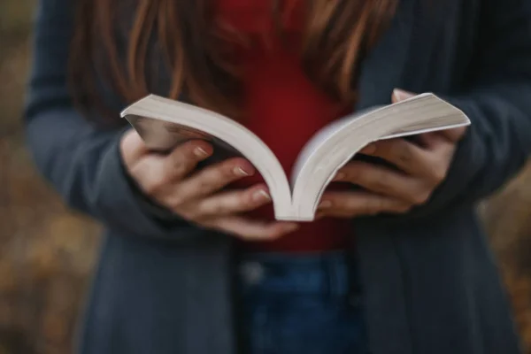 Tutan kadın kitap açtı. Okuma outdooron sonbahar park modeli. Sonbahar. Açık.