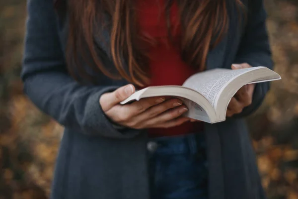 Sıcak giysiler tutan kadın kitap resim açık sonbahar önündeki açıldı