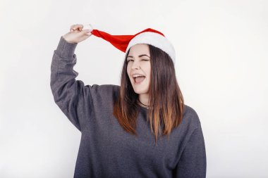 Kameraya poz ve wink veren Sunta Claus şapka neşeli ve komik genç kadın