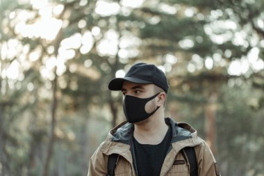 Ağaçların arkasında tıbbi maskeli bir adamın portresi.