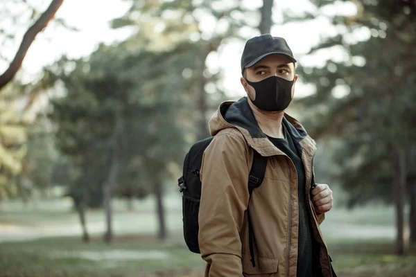 Tıbbi maskeli adam parkta yürüyor. 