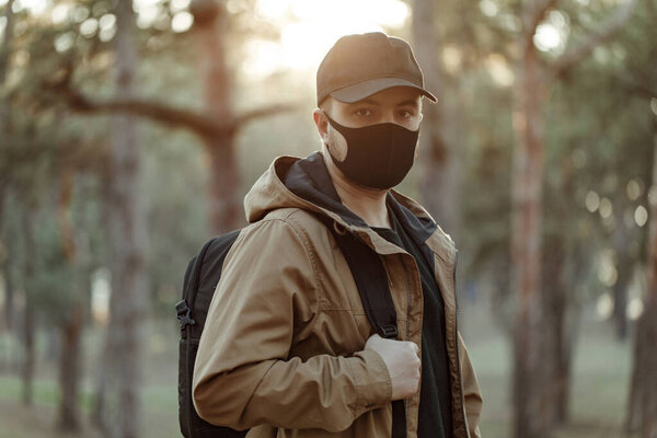 Ходячий человек в черной медицинской маске. Мужчина ходит по парку с рюкзаком
.