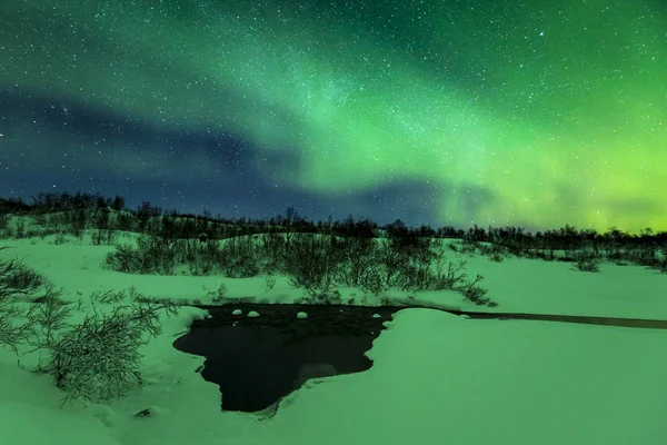 Luces boreales sobre un arroyo de agua en un paisaje invernal . — Foto de Stock