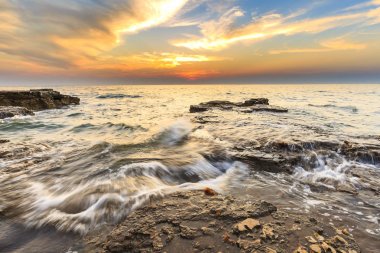 Adriat üzerinde taşlarla bir plajda renkli Günbatımı keyfi