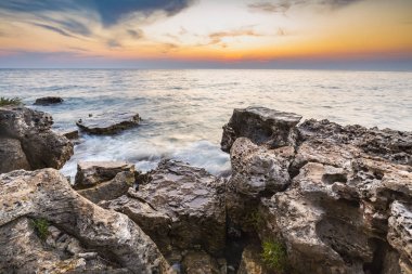 Adriat üzerinde taşlarla bir plajda renkli Günbatımı keyfi