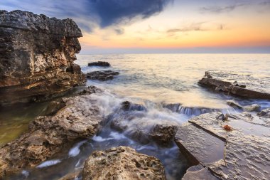 Adriat üzerinde taşlarla bir plajda renkli Günbatımı keyfi