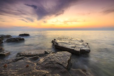 Adriat üzerinde taşlarla bir plajda renkli Günbatımı keyfi