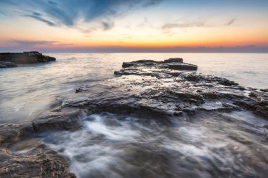 Adriat üzerinde taşlarla bir plajda renkli Günbatımı keyfi