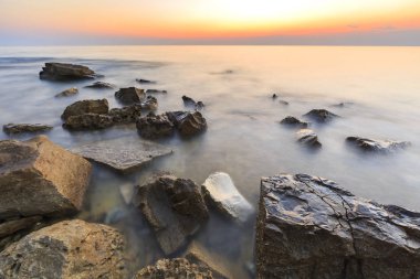 Adriat üzerinde taşlarla bir plajda renkli Günbatımı keyfi