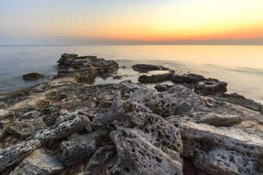 Adriat üzerinde taşlarla bir plajda renkli Günbatımı keyfi