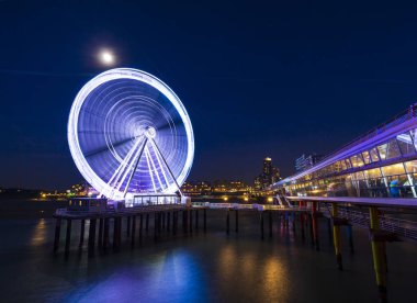Gece ay ışığı altında iskelede ışıklı dönme dolap. Scheveningen, Lahey arka planda, popüler turistik seyahat hedef.