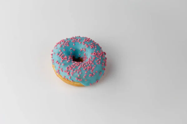 Donut with blue glaze and pink sprinkles isolated on white background. Top view. — Stock Photo, Image