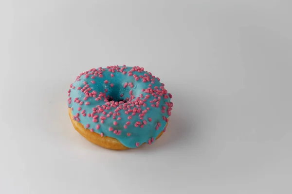 Donut with blue glaze and pink sprinkles isolated on white background. Top view. — Stock Photo, Image