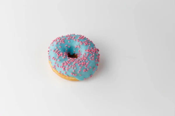 Donut med blå glasyr och rosa strössel isolerad på vit bakgrund. Ovanifrån. — Stockfoto