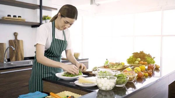 Asyalı kadınlar sağlıkla ilgilenirler. Sebze salatasını karıştırırlar. Mutlu aile kavramı, modern mutfak.,