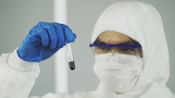 Coronavirus Covid 19, Coronavirus covid 19 araştırma laboratuarındaki erkek bilim adamı biyolojik tehlike koruma giysisinin numune tüpünden enfekte olmuş kan örneği.,