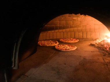 İtalyan pizzacıda ahşap fırın ve pişirilmiş pizzalar.