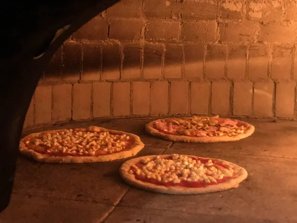Wood oven in an Italian pizzeria with pizzas being cooked