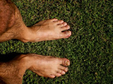 Yeşil çimenlikte bir adamın iki ayağı