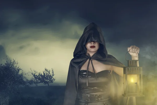 Young asian witch woman in black corset and cloak hooded with lantern — Stock Photo, Image