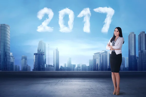 Smiling asian business woman standing beside cloud shaped number 2017 — Stock Photo, Image