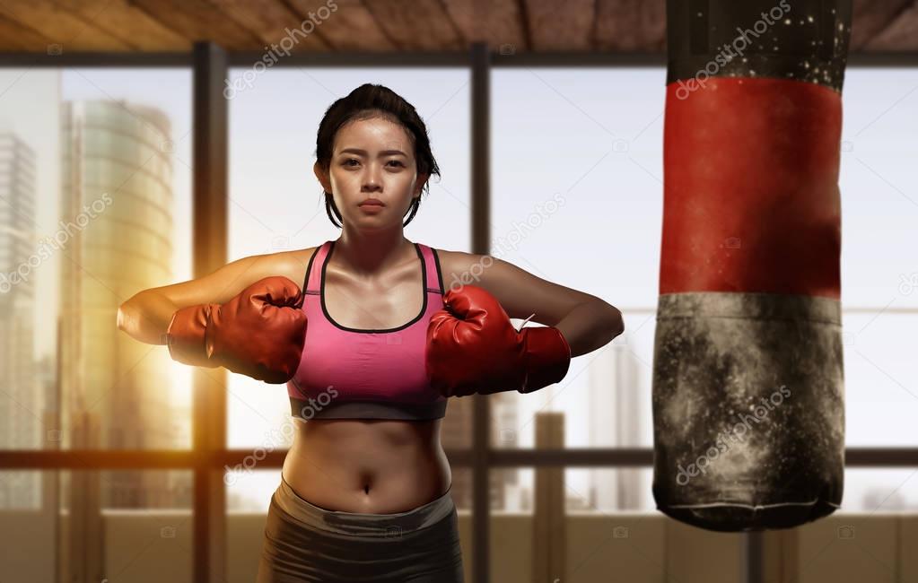 Pretty asian girl boxer doing exercise with punching bag