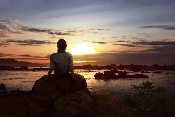 Mujer sentada en la roca al atardecer — Foto de Stock