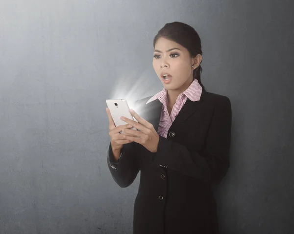 Femme d'affaires utilisant un smartphone avec une expression choquée — Photo